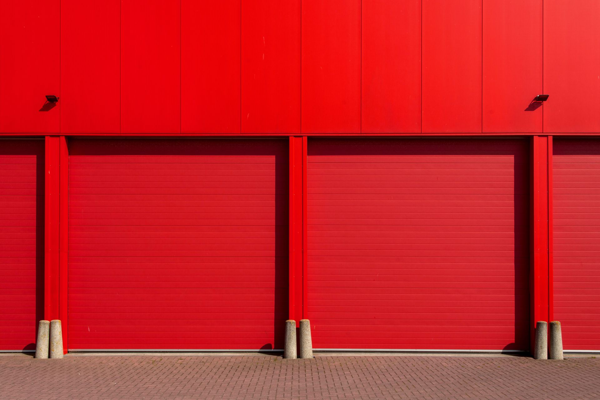 Vivid red garage doors in a sleek industrial building, exuding modern architecture.